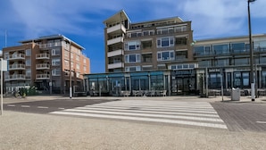 Un bâtiment moderne à plusieurs étages, avec un café situé au rez-de-chaussée et une enseigne visible depuis la rue.