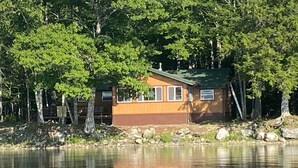 A cabin by a lake surrounded by trees.