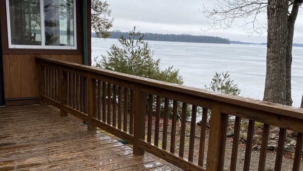 A wooden deck with a railing overlooking a body of water.