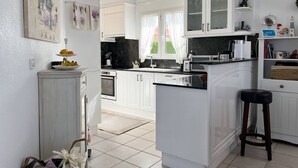 Una cocina moderna con muebles blancos, una isla central y un comedor con un taburete de bar.