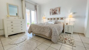 Un dormitorio con una cama, un tocador, una mesita de noche y un cuadro en la pared.