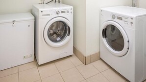 Una sala de bugaderia amb dues rentadora blanques i una eixugadora blanca.