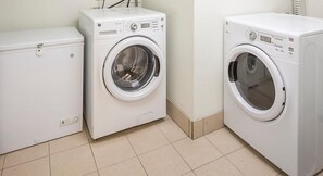 Une buanderie équipée de deux machines à laver blanches et d’un sèche-linge blanc.