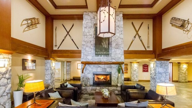 A spacious lobby with a stone fireplace, leather sofas, and a wooden ceiling. - Slope-side condo ski in ski out! Quiet side of resort, heated pool + 3 hot tubs (Whistler)