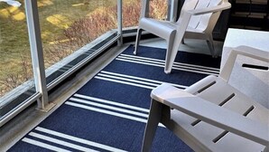 A balcony with a view of a forest and a body of water. There are two Adirondack chairs and a small table. - Slope-side condo ski in ski out! Quiet side of resort, heated pool + 3 hot tubs (Whistler)
