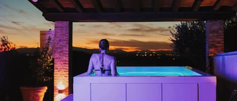 A person standing at a poolside area with a sunset view in the background.