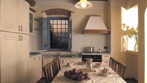 Una cocina con armarios de madera, una mesa de comedor con mantel floral y una ventana que ofrece vistas al exterior.