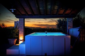A hot tub under a covered patio with a sunset view.
