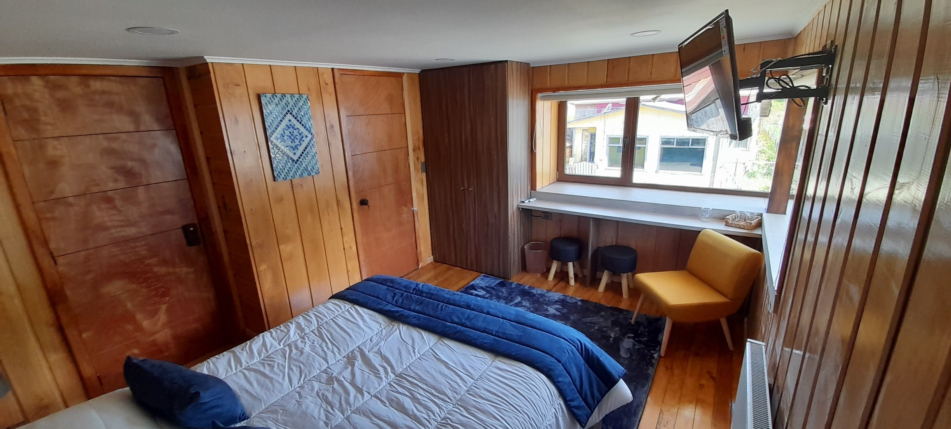 Ein Schlafzimmer mit Bett, Schreibtisch, Stuhl und Fenster.