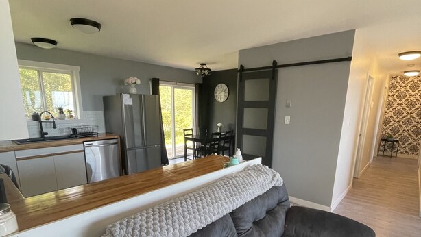 A modern living room with a grey sofa, a wooden coffee table, and a kitchen in the background.