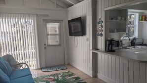 A compact kitchen with a TV mounted on the wall, a coffee maker, and a sink.