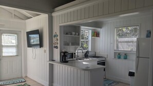 A compact kitchen with white cabinetry, a built-in stove, a sink, and a refrigerator.
