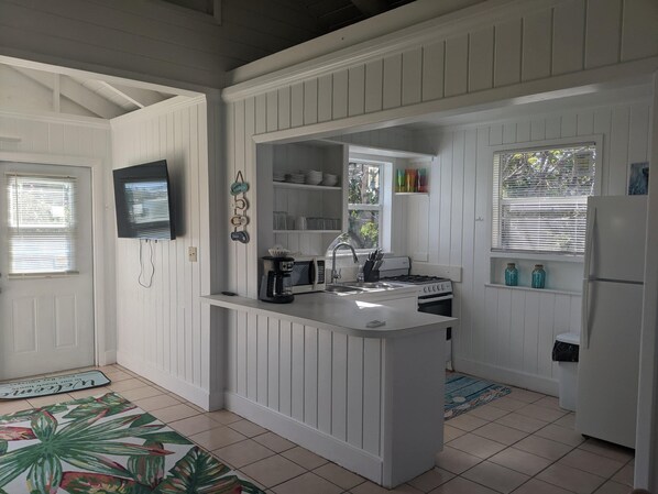A compact kitchen with white cabinetry, a built-in stove, a sink, and a refrigerator.