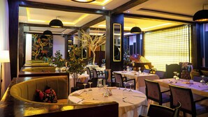 Een restaurant met ronde tafels, zwarte stoelen en hanglampen.
