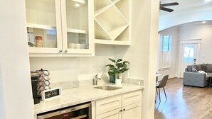 Una cocina moderna con armarios blancos, horno empotrado y espacio para café.