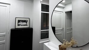 A hallway with a large mirror, a framed picture on a cabinet, and a small plant on a ledge.