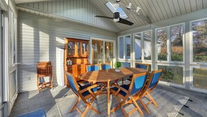 A covered patio with a wooden table and blue chairs, a ceiling fan, and a view of the outside. - Lenox Grand Colonial with Pool by Evergreen Home (Lenox)