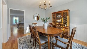 A dining room with a wooden table, chairs, a chandelier, and a cabinet. - Lenox Grand Colonial with Pool by Evergreen Home (Lenox)