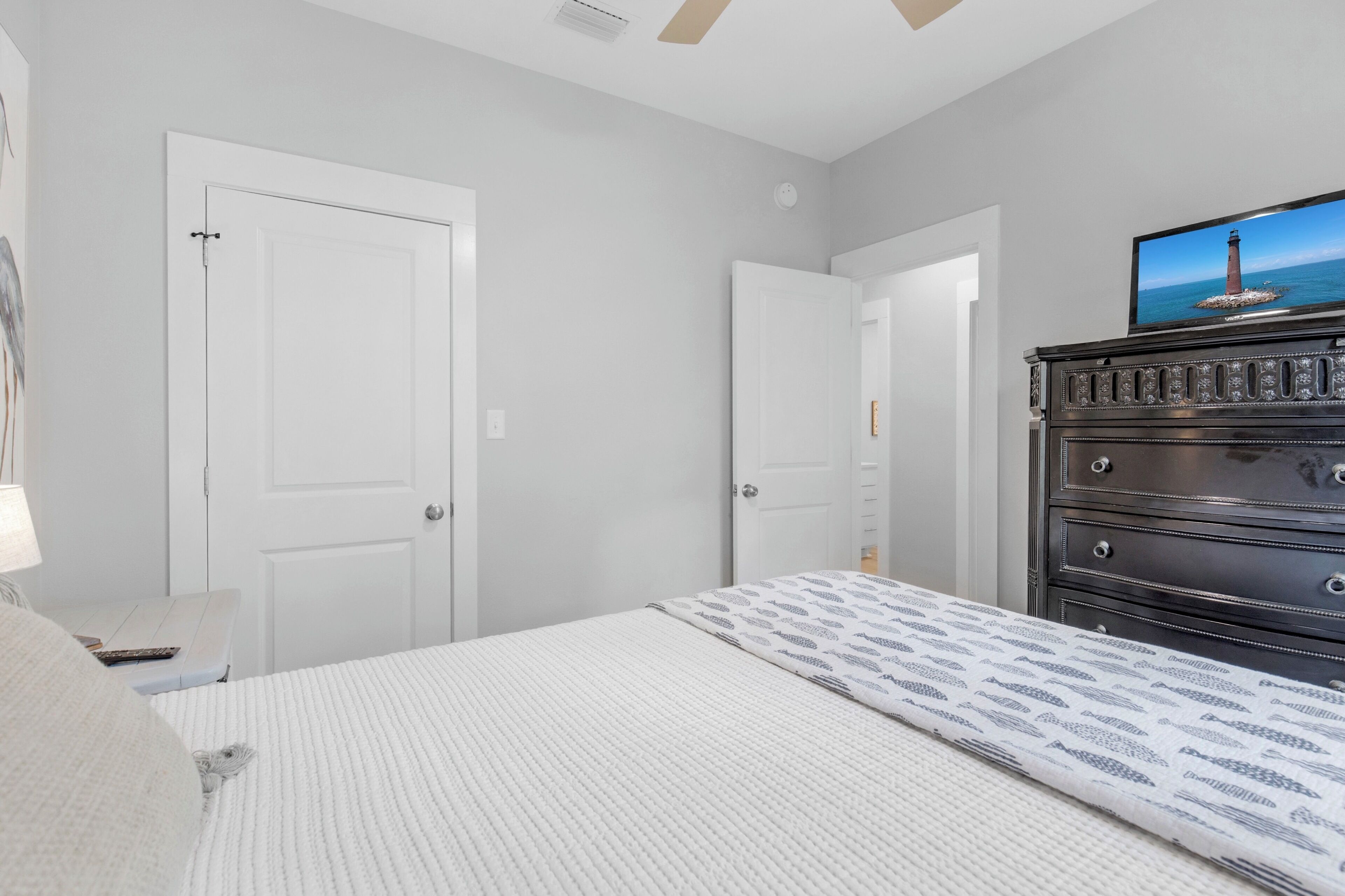 A bedroom with a bed, dresser, and television.