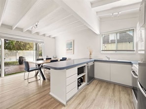 A modern kitchen with a large island, built-in appliances, and a dining area with a table and chairs.