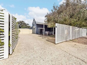A residential property with a paved driveway, a fenced area, and a building with a sloped roof.