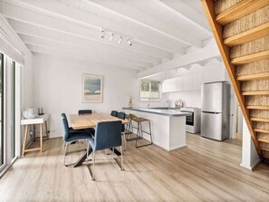 A modern kitchen with white cabinets, a central island, and a built-in oven.