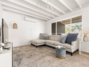 A modern living room with a sectional sofa, a coffee table, and a large window with blinds.