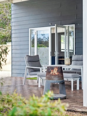 An outdoor patio with a table and chairs, a fire feature, and a sliding glass door leading to a covered area.