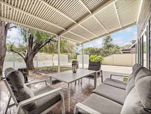 An outdoor patio with a covered seating area, a table, and a potted plant.