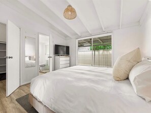 A bedroom with a large bed, a wardrobe, a television, and a window with blinds. - Pepper Cottage — Cosy Central Stay (Dunsborough)