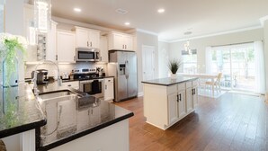 Una cocina moderna con gabinetes blancos, electrodomésticos de acero inoxidable y una encimera de granito.