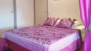 Un dormitorio con cama, dos puertas, un espejo y una cortina.