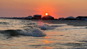 A beach with waves, a sunset, and houses in the background. - Gulf Front!! 2 Master Suites- Steps Away from the Beach!! (Dauphin Island)