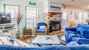 A living room with a fireplace, blue furniture, and a 'Family' sign on the wall. - Gulf Front!! 2 Master Suites- Steps Away from the Beach!! (Dauphin Island)