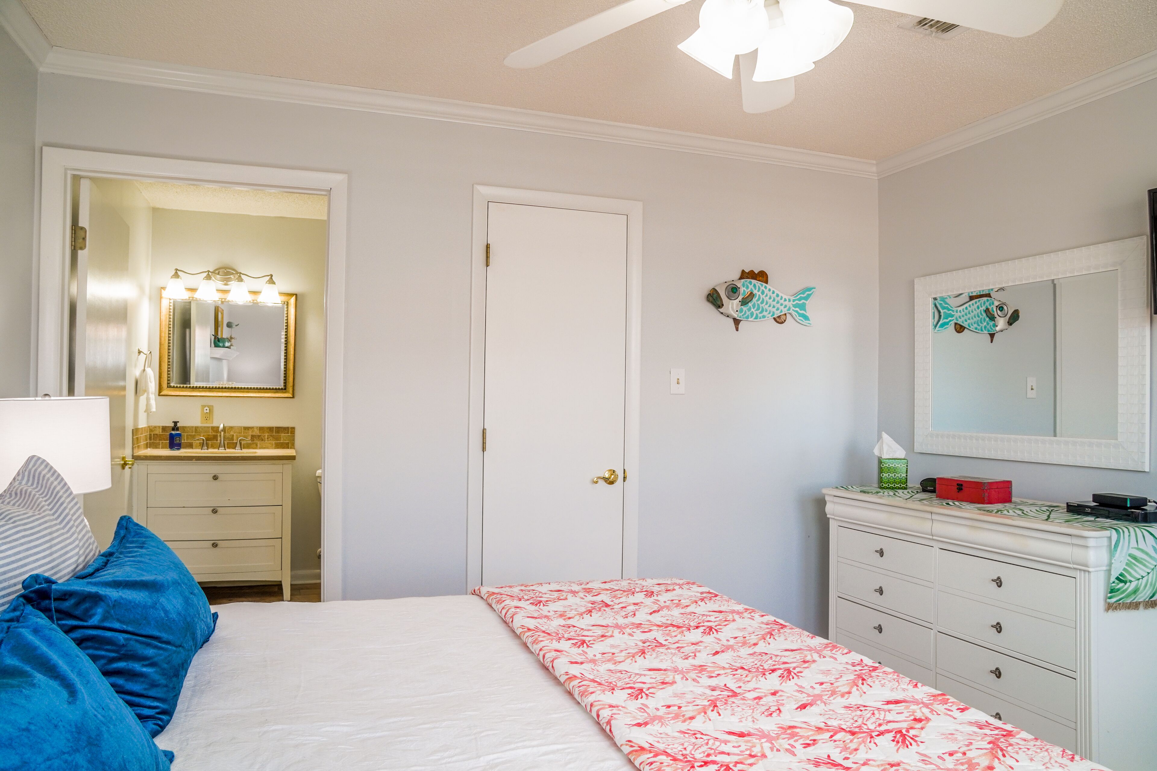 A bedroom with a bed, a dresser, a mirror, and a door.