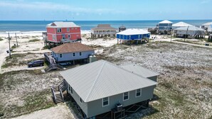 A beachfront property with multiple houses, including a prominent red house and a blue house with a covered porch. - Gulf Front!! 2 Master Suites- Steps Away from the Beach!! (Dauphin Island)