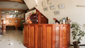 Un área de recepción con mostrador de madera, certificados enmarcados en la pared y una planta en maceta.