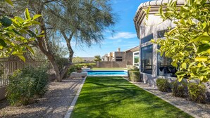 Un patio trasero bien cuidado con piscina, rodeado de diversas plantas y árboles.