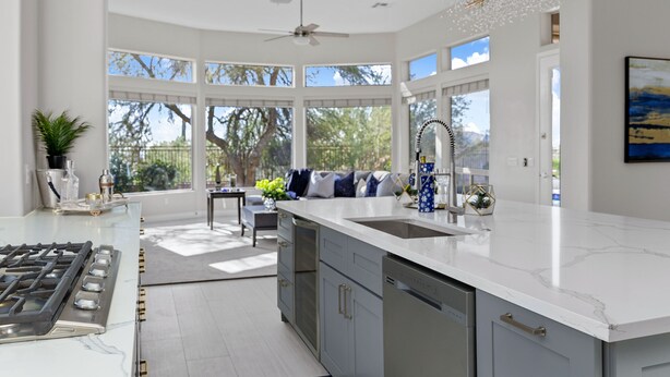 Una cocina moderna con una isla grande, electrodomésticos integrados y vistas al exterior.