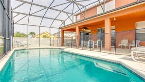 Piscina com teto de vidro, rodeada por espreguiçadeiras e um espaço de estar coberto.