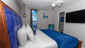 A bedroom with a bed, a ceiling fan, a TV, and a window with a view. - New Modern Ocean View 2Bed2Bath Hip Strip (Montego Bay)