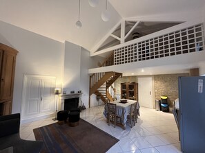 A spacious kitchen with a dining area, a fireplace, and a staircase leading to an upper level. - Charentais house renovated in 2020 (Saint-Georges-d'Oléron)