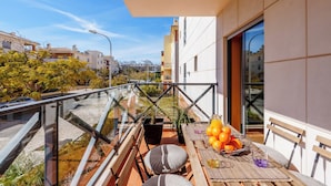 A balcony with a table set for dining, potted plants, and a view of the cityscape. - Modern & Spacious Flat with Pool close to Oura (Albufeira)