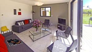 A modern living room with a sofa, chairs, a coffee table, and a TV. - KERPI, Very spacious house, 3 minutes' walk from Kerbourgnec beach (Saint-Pierre-Quiberon)
