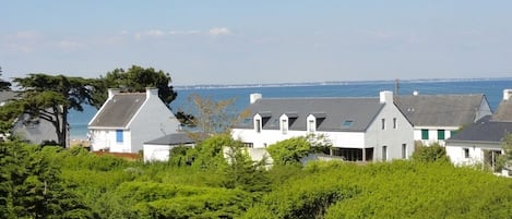 A coastal residential area with houses, greenery, and a view of the sea.