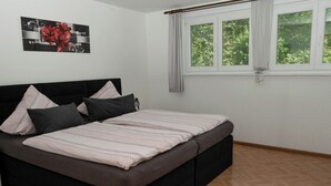 A bedroom with a bed, pillows, a window with curtains, and a wall with a picture. - Vacation apartment Panoramablick (Oberharmersbach)