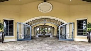 Una entrada cubierta con una fuente central, puertas arqueadas y detalles de metal decorativo.