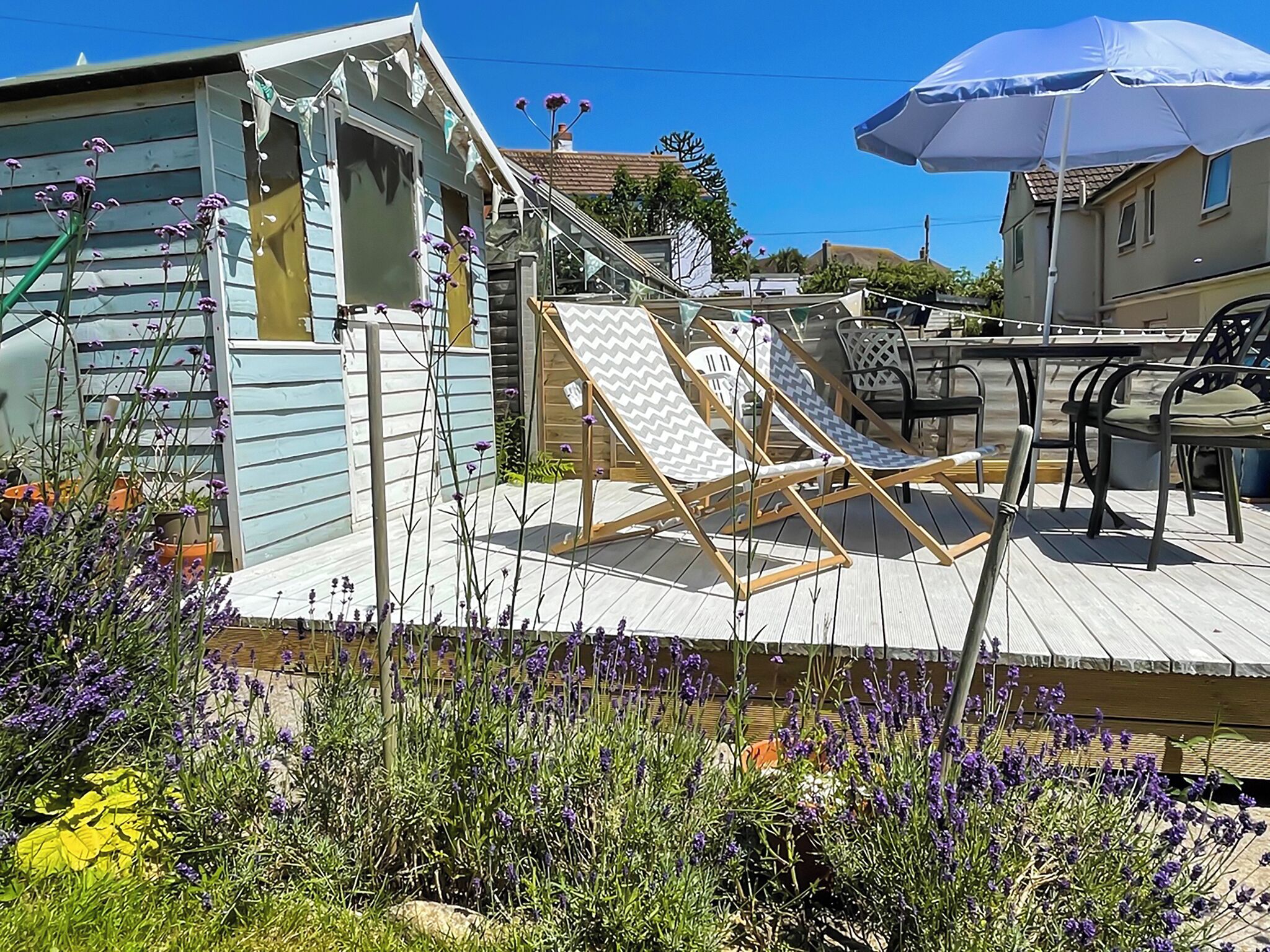 Eine Terrasse mit zwei Liegestühlen, einem Tisch und Stühlen.