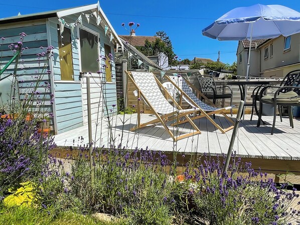 A deck with two sun loungers, a table, and chairs.