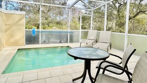 Un espace extérieur abrité comprenant une piscine, des chaises longues et une table.
